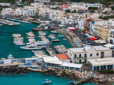 Capri Adası, İtalya 'da canlı bir liman. Turkuaz sularda kayıklar, renkli binalar ve rıhtım boyunca kalabalık var..