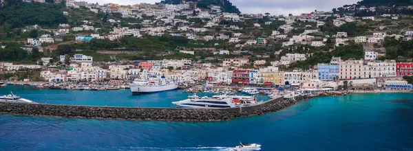 İtalya 'nın Capri Adası' ndaki Marina Grande 'de canlı binalar, yatları, feribotları, turkuaz suları ve yemyeşil bir yamaçtan oluşan yoğun bir liman bulunuyor..