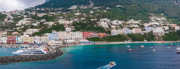 Capri Adası, İtalya 'daki canlı Marina Grande' de renkli binalar, yatlar, botlar, feribot, turkuaz sular ve yemyeşil bir tepe zemini var..