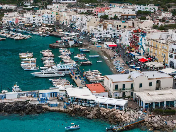 Capri Adası, İtalya 'da canlı bir liman. Turkuaz sularda kayıklar, renkli binalar ve rıhtım boyunca kalabalık var..