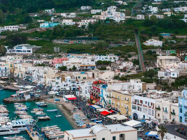 Capri Adası, İtalya 'da canlı bir yat limanı. İçinde tekneler, renkli binalar, yamaçta funicular demiryolu, yemyeşil ve canlı bir rıhtım var..