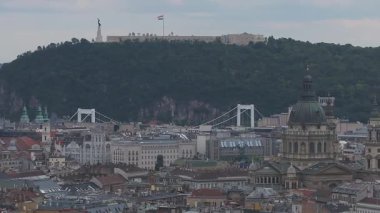 Budapeşte, Macaristan 'ın hava manzarası, St. Stephen Bazilikası' nın sergilendiği, kırmızı çatılı evleri olan yeşil bir tepe, ve şehir manzarası boyunca yavaş bir tava..