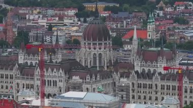 Macar Parlamento Binası 'nın havadan görünüşü kırmızı bir vinç ile, yerleşim binaları, yeşillikler ve Tuna Nehri ile çevrili..