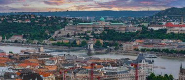 Budapeşte, Macaristan 'ın hava manzarası, tepenin üzerindeki Buda Kalesi, Tuna Nehri üzerindeki Zincir Köprüsü ve vinçli kırmızı çatılı binalar.