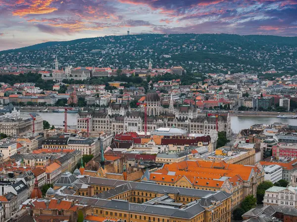 Macaristan 'ın Budapeşte kentinin havadan görünüşü, Tuna Nehri, Buda Tepeleri, Gellert Tepesi yakınlarındaki Macar Parlamentosu binası ve renkli bir günbatımı gökyüzü..