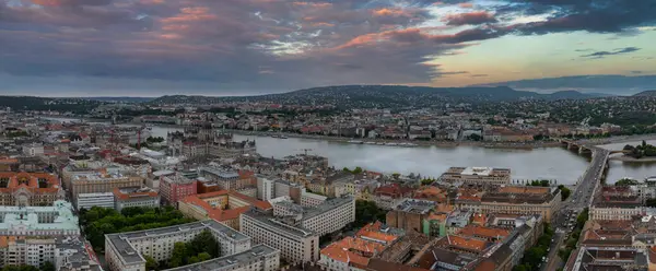 Tuna Nehri, Macaristan Parlamento Binası, Margaret Köprüsü ve dramatik bir gökyüzü altında yuvarlanan tepelerin yer aldığı Budapeşte, Macaristan 'ın hava manzarası.