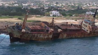 Kıbrıs kıyısı yakınlarındaki Edro III gemi enkazının hava görüntüsü paslı yapıyı, kumlu sahili, kayalık kıyı şeridini ve yakındaki beyaz binaları gösteriyor..
