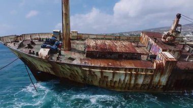 Kıbrıs Rum Kesimi 'nin kayalık kıyısı yakınlarındaki Edro III enkazının hava manzarası. Paslı gövde, zincirler, kayalıklar ve nazik dalgalar dinamik bir kıyı manzarası yaratır..