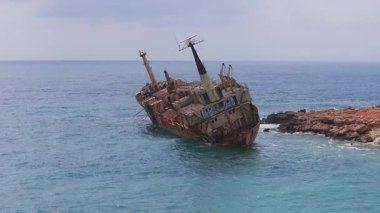 Kıbrıs yakınlarındaki Edro III enkazının hava görüntüsü, paslı gemiyi mavi sularda, engebeli kayalıklarda ve arka planda bir kıyı yerleşiminde gösteriyor..