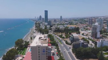 Kıbrıs 'ın Limasol kentinin hava görüntüsü, modern gökdelenler, kumlu bir plaj, Akdeniz ve ön planda havuzu olan bir otel gösteriyor..