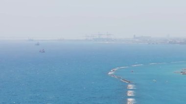 Kıbrıs 'ın Limasol kentinin havadan görünüşü, kıyı şeridini, modern binaları, dalgakıranları, bir gökdeleni, vinçli bir limanı ve Akdeniz' i gösteriyor..