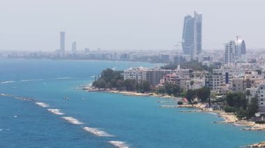 Kıbrıs Rum Kesimi 'nin Limasol kentinin havadan görünüşü, yüksek gökdelenler, basamaklı bir yapı ve modern ve geleneksel mimarinin bir karışımına sahip yavaş bir tava içeriyor..