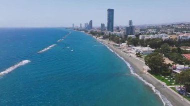 Kıbrıs 'ın Limasol kentinin hava manzarası, modern gökdelenleri, kumlu plajları, berrak mavi suları ve Akdeniz kıyı şeridi boyunca uzanan rıhtımları gösteriyor..