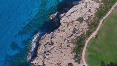 Ayia Napa 'nın kıyı şeridi üzerindeki yavaş bir tepside turkuvaz suları, sağdaki kayalık oluşumlar ve Kıbrıs Rum Kesimi' ndeki canlı sualtı ayrıntıları ortaya çıkıyor..