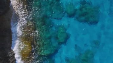 Ayia Napa 'nın Kıbrıs' taki kıyı şeridinin havadan görünüşü, Aşk Kemeri kaya oluşumu, turkuaz sular ve kayalık kıyı boyunca hafif dalgalar yer alıyor..