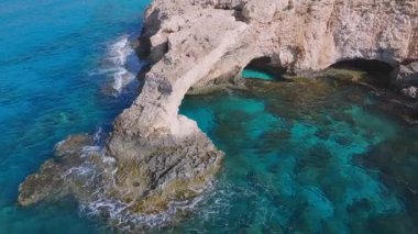 Kıbrıs Rum Kesimi 'nin Ayia Napa kentindeki Aşk Kemeri' nin yumuşak üstgeçişi, doğal kaya oluşumunu, turkuaz suları ve kıyı boyunca hafif dalgaları gözler önüne seriyor..