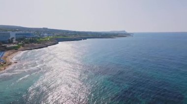 Kıbrıs Rum Kesimi 'nin Ayia Napa kentinin hava manzarası, engebeli uçurumlar, pırıl pırıl Akdeniz suları ve dağınık yeşillikleri olan bir tatil köyü.