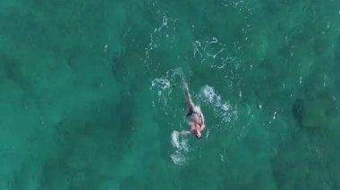 Kıbrıs 'ın Ayia Napa kenti yakınlarındaki kristal berrak turkuaz sularda yüzen bir adam. Hava perspektifi onun hareketlerini ve dingin denizde dalgalanmalarını yakalar..