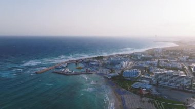 Kıbrıs Rum Kesimi 'nin Ayia Napa kentinin hava temizliği, gün batımında kıyı şeridi, kumlu plajlar, marina, modern tatil beldeleri ve şehir planlarını gözler önüne seriyor..