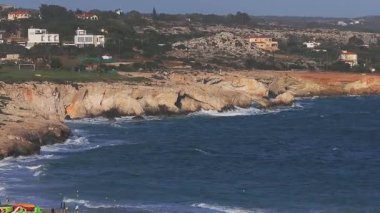 Kıbrıs Rum Kesimi 'nin Ayia Napa kentinin hava manzarası canlı mavi suları, engebeli turuncu uçurumları, beyazlatılmış binaları ve kıyı şeridi boyunca hafif dalgaları gösteriyor..