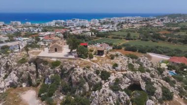 Kıbrıs Rum Kesimi 'nin Ayia Napa kentindeki kayalık bir tepedeki St. Elias Kilisesi' nin hava manzarası. Kamera kasabanın, yeşil tarlaların ve Akdeniz 'in üzerinde dönüyor..