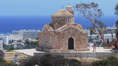 Kıbrıs Rum Kesimi 'nin Ayia Napa kentindeki St. Elias Kilisesi' nin hava manzarası, taş mimarisini, terracotta çatısını, asfalt avlusunu ve çevresini gösteriyor..