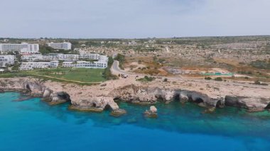 Kıbrıs Rum Kesimi 'nin Ayia Napa kentinde kayalık kayalıklar, turkuaz Akdeniz suları, deniz mağaraları ve seyrek bitki örtüsü üzerindeki tatil beldelerini gösteriyor..