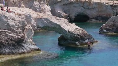 Ayia Napa 'nın Aşk Kemeri oluşumu, turkuvaz suları, engebeli uçurumlar, doğal mağaralar ve insanların tırmanıp yüzdüğü hafif su hareketleri..