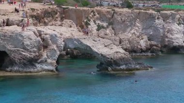 Kıbrıs Rum Kesimi 'nin Ayia Napa kentindeki Aşk Kemeri kaya oluşumu turkuaz sularla çevrilidir. İnsanlar yürür, kemerde durur, ve aşağıda canlı bir sahnede yüzerler..