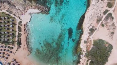 Ayia Napa 'nın berrak turkuaz suları ve engebeli kayalık kıyı şeridi üzerinde pürüzsüz bir insansız hava aracı uçuşu, sualtı kaya oluşumları ve kıyı arazisi sergiliyor..
