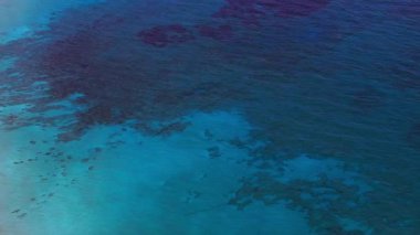 Kıbrıs Rum Kesimi 'nin Ayia Napa kenti yakınlarındaki açık mavi suların havadan görünüşü, sualtı kaya oluşumları, kırmızı bir şamandıra ve deniz üzerinde düzgün bir dönüş hareketi..