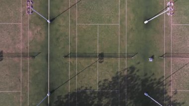 Kıbrıs Rum Kesimi 'nin Ayia Napa kentindeki bir tenis kortu kompleksinin havadan görünüşü, kırmızı bougainvillea, park alanları ve yavaş insansız hava aracı hareketleriyle çevrili.