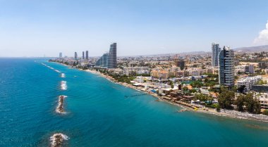 Modern gökdelenler, kentsel binalar, turkuaz Akdeniz suları, dalgalar ve açık mavi gökyüzünün yer aldığı Limasol, Kıbrıs 'ın hava manzarası.