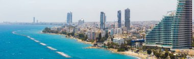 Kıbrıs 'ın Limasol kentinin hava manzarası, yüksek binalar, kumlu plajlar, kayalık çıkıntılar, palmiye ağaçları ve derin mavi Akdeniz manzarası.