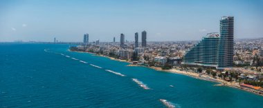 Yüksek binalar, eğri büğrü modern bir yapı, Akdeniz ve kıyı şeridi yakınlarındaki teknelerin yer aldığı Kıbrıs 'ın Limasol kentinin havadan görünüşü.