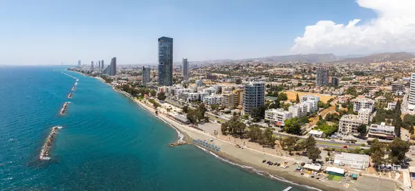 Akdeniz, kumlu plaj, dalgalı sular, modern gökdelenler, kentsel yayılma ve hareketli tepelere sahip Limasol, Kıbrıs 'ın hava manzarası.