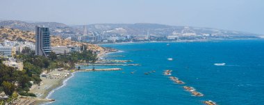 Kıbrıs Rum Kesimi 'nin havadan görünüşü modern yüksek yükseliş, kumlu plajlar, dalgalar, berrak mavi sular, yemyeşil alanlar ve arka planda yuvarlanan tepeleri gösteriyor..