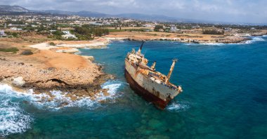 Edro III Batığı, Kıbrıs 'ın Paphos kentinin kayalık kıyıları yakınında, turkuaz suları, engebeli kıyı şeridi ve parçalı bulutlu bir gökyüzü ile çevrilidir..
