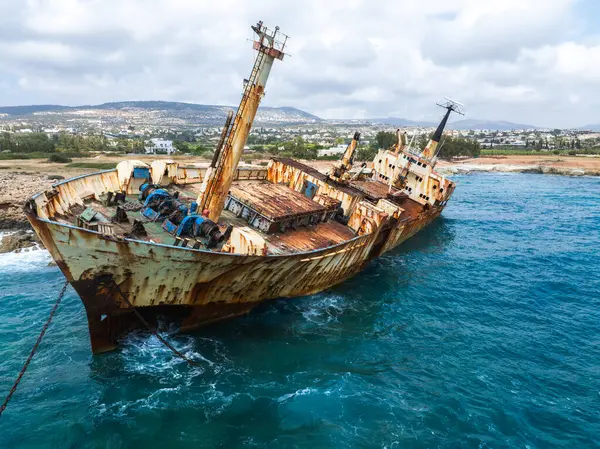 Edro III Batığı, paslanmış gövdesi, kırık direkleriyle, mavi sularıyla, kıyı kasabası ve görülebilir yuvarlanan tepeleriyle Kıbrıs 'ın kayalık kıyılarına yakın duruyor..