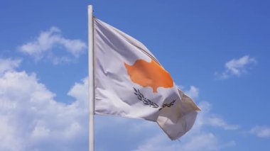 Kıbrıs bayrağı rüzgarda dinamik bir şekilde dalgalanırken, güneşli bir günde turuncu haritasını ve zeytin dallarını sergiliyor..
