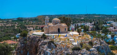 Taş, Profitis İlyas Kilisesi 'ni tırabzanlar, bayraklar, yemyeşil alanlar, dağınık evler ve mavi gökyüzünün altında ufuk çizgisi olan bir tepenin üzerine inşa etti..