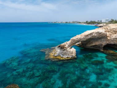 Kıbrıs Rum Kesimi 'nin Ayia Napa kentindeki kıyı manzarası, turkuvaz suları, kumlu plajlar ve kıyı şeridi boyunca uzanan lüks tatil beldeleri üzerinde doğal bir kaya aşkı kemeri..