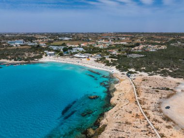 Kıbrıs 'ın Ayia Napa kentinin hava manzarasında turkuaz sular, güneşli kumlu plajlar, lüks tatil beldeleri, yemyeşil oteller ve kayalık bir kıyı şeridi görülüyor..
