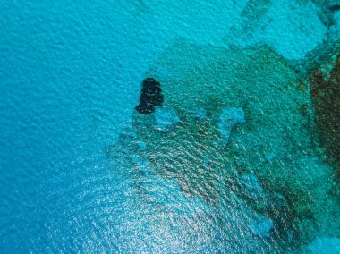 Kıbrıs 'ın Ayia Napa kenti yakınlarındaki canlı turkuaz suların hava manzarası, mavi ve yeşil denizin değişkenliğiyle çelişen koyu kayalık bir oluşum içeriyor..