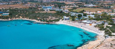 Kıbrıs Rum Kesimi 'nin Ayia Napa kentindeki Nissi Sahili' nin hava manzarasında turkuaz sular, güneşli kumlu kıyılar, tatil beldeleri ve deniz yüzücüleri görülüyor..