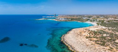 Kıbrıs 'ın Ayia Napa kentinin hava manzarası, Nissi Sahili, turkuaz sular, lüks tatil beldeleri, modern bir otel kulesi ve kentsel ve doğal manzaraların karışımı.