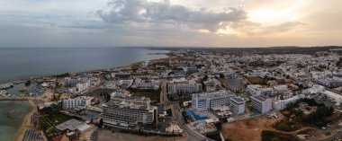 Kıbrıs Rum Kesimi 'nin Ayia Napa kentinin hava perspektifi, lüks oteller, kumlu plajlar, tekneli bir marina ve Akdeniz yakınlarındaki kentsel alanları gösteriyor.