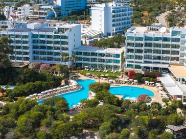 Kıbrıs Rum Kesimi 'nin Ayia Napa kentindeki modern tatil köyünde geniş bir havuz, güneşli şezlonglar, peyzaj bahçeleri, palmiye ağaçları ve canlı Akdeniz çevresi bulunuyor..