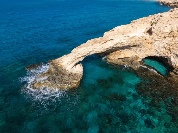 Kıbrıs Rum Kesimi 'nin Ayia Napa kentindeki Aşk Köprüsü kayalıkları, engebeli uçurumlar ve canlı mavi bir denizle çevrili berrak turkuaz suların üzerinde uzanır..