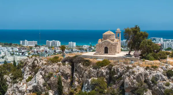 Taş, Profitis Ilias Kilisesi 'ni Kıbrıs' ın Ayia Napa kentindeki bir tepenin üzerine inşa etti. Arka planda Akdeniz, modern tatil beldeleri ve güneşli gökyüzü vardı..